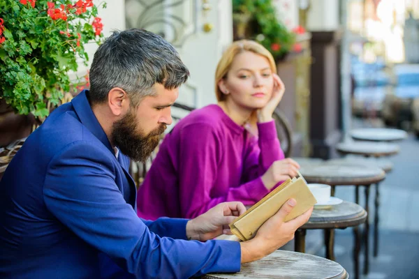 Man and woman sit cafe terrace. Girl interested what he reading. Literature common interest. How to find girlfriend with common interest. Guide to dating. Meeting people with similar interests