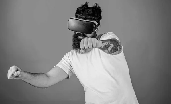 Concept de course virtuelle. Hipster sur le visage confiant vélo de conduite à grande vitesse en réalité virtuelle. Guy jouer jeu de course en VR. Homme avec barbe en lunettes VR conduite moto, fond rouge — Photo