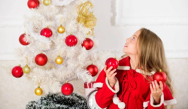 Menina sorridente rosto segurar bolas ornamentos fundo interior branco. Como decorar a árvore de Natal com a criança. Deixe a criança decorar a árvore de Natal. Parte favorita de decoração. Obtendo criança envolvida decoração — Fotografia de Stock