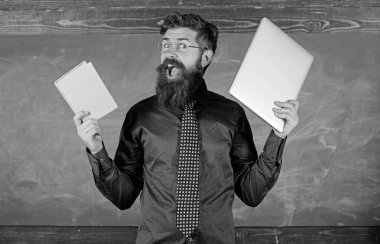 Modern teknolojiler yarar. Modern teknoloji ile kal. Öğretmen sakallı hippi kitap ve laptop tutar. Öğretmen modern öğretim yaklaşımı seçme. Dijital kağıt karşı. Şu öğretim yöntemi seçin