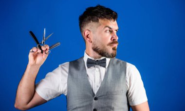 Berber Kuaför Salonu. İpuçları bakım Kuaför sakal. Erkek yelek papyon ile usturanın mavi arka plan tutun. Vintage sanat kavramı berber. Kuaför sakallı hippi keskin ustura ile