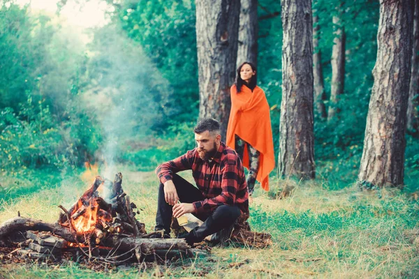 Biralı maço şenlik ateşinin yanında oturuyor, karısıyla tatile çıkıyor.. — Stok fotoğraf