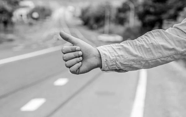 Самый популярный способ автостопом является большой палец вверх. Ручной большой палец вверх жест попробуйте остановить автомобиль на заднем плане. Автостоп с большим пальцем или жестом. Убедитесь, что вы правильно жестикулируете, чтобы остановить машину — стоковое фото