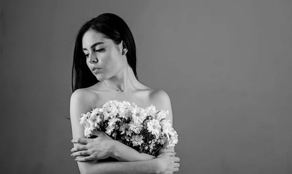 Donna che nasconde i seni, copre con bouquet. Immagine di donna tiene mazzo di bei fiori di camomilla, sfondo grigio. Cancro del concetto di seno. Lady copre seni con fiori, sfondo grigio — Foto Stock