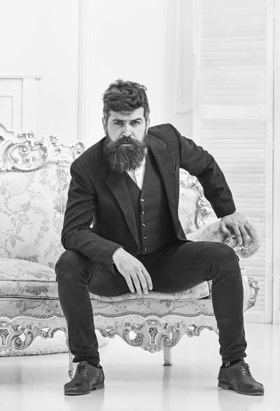 Macho atractivo y elegante en serio, cara pensativa sentado en el sofá de lujo a la antigua. Concepto masculinidad. Hombre con barba y bigote con traje clásico, elegante atuendo de moda — Foto de Stock