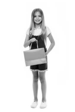 Küçük kız Alışverişkoliğin gülümseme ile alışveriş çantası üzerinde beyaz izole. Mutlu kız kağıt torba tutun. Çocukluk. Çocuk shopper moda tulum. Tatil hazırlanması ve kutlama. Alışveriş ve satış