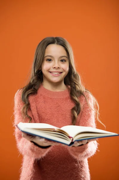 Kinder lesen gerne Bücher. Buchhandelskonzept. wunderbare kostenlose Kinderbücher zum Lesen. Lesepraxis für Kinder. Kinderliteratur. Mädchen halten Buch lesen Geschichte auf orangefarbenem Hintergrund — Stockfoto