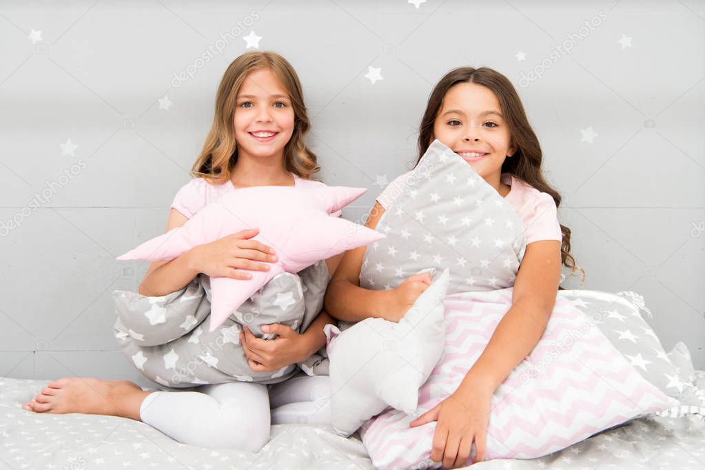 Girls happy best friends or siblings in cute stylish pajamas with pillows sleepover party. Sisters play pillows bedroom party. Pillow fight pajama party. Evening time for fun. Sleepover party ideas