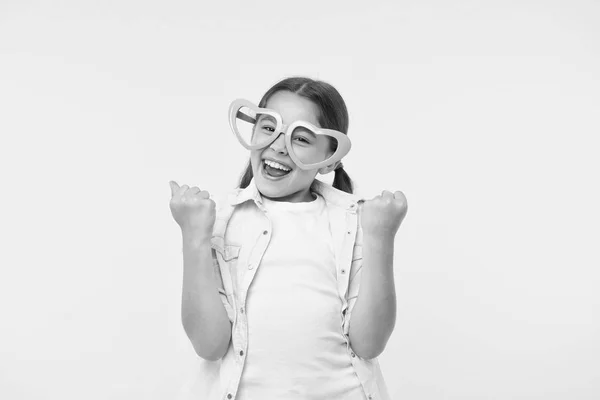 Niño feliz usar gafas en forma de corazón sobre fondo amarillo. Niña sonrisa en accesorio de moda. Belleza de estilo funky. Día de San Valentín. La vida es demasiado corta para llevar ropa aburrida. — Foto de Stock