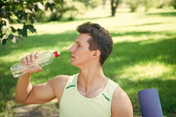 Sportler trinkt Wasser an sonnigem Tag in natürlicher Sommerlandschaft — Stockfoto