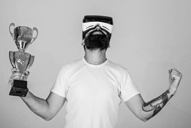 Şampiyonluğa ulaştı, Vr gözlüklü elinde altın kadehi tutun. Vr bardaklarda sakallı adam kazanan, gri arka plan var. Hipster mutlu yüz üzerinde sanal şampiyonluğa ulaştı. Sanal başarı kavramı