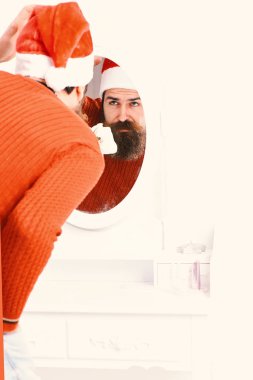 Noel Baba aynaya bakar. Adam aynaya doğru eğiliyor..