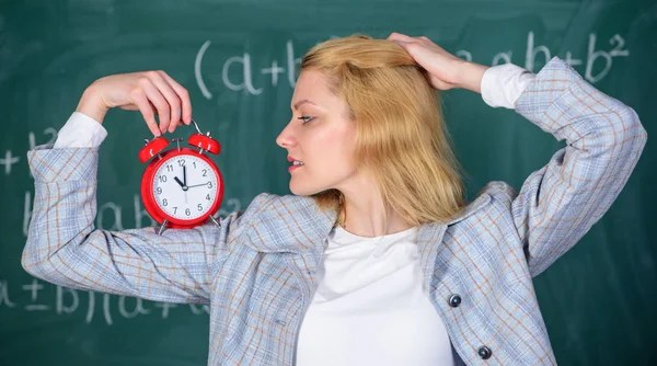 Gesunder Tagesablauf. Erzieher beginnen Unterricht. Disziplin ist ihr wichtig. Lehrerin hält Wecker. Unterrichtszeitkonzept. Zeit für eine Pause. Mädchen fragen sich über die Zeit. Willkommen Lehrer Schuljahr — Stockfoto