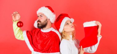 Noel çorap geleneği. Kadın ve santa şapka Noel kırmızı arka plan bekleyen sakallı adam. Çift Noel Noel Baba kostüm çorap ve süsleme topu tutun. Noel kutlamaları kavramı