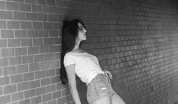 Girl alone posing brick wall background. Woman lean on wall hang out in porch. She waiting for someone. Girl attractive brunette relaxing hang out underground crossing or subway. Underground culture