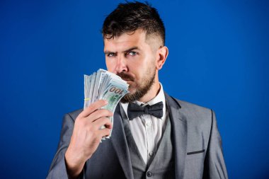 İşadamı nakit para var. Zenginlik ve refah kavramı. Nakit para kolay ve hızlı bir şekilde almak. Para gibi kokuyor. Kolay nakit krediler. Resmi takım elbise tutun doları banknot yığını mavi arka plan