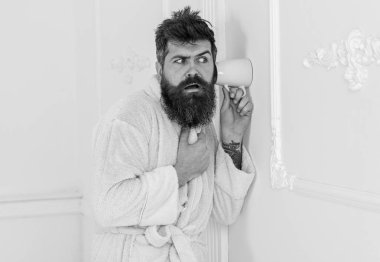 Casusluk, gizli dinleme beyaz iç adam. Gizli ve casus kavramı. Adam sakal ve bıyık kupa duvarının yakınında kullanarak eavesdrops. Hipster katı yüz bornoz içinde gizlice konuşma dinle