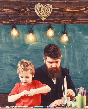 Yetenek ve yaratıcılık kavramı. Çocuk ve resim, çizim meşgul yüzleri öğretmen. Sakal, baba ve küçük oğul çizerken, sınıfta oluşturma, kara tahta arka plan ile öğretmen