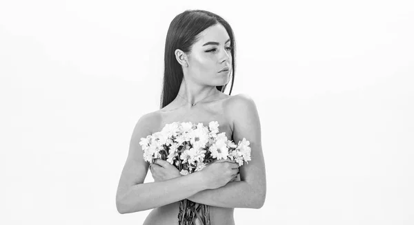 Ragazza sul viso calmo sta nudo e tiene fiori di camomilla davanti al petto. La signora copre i seni con dei fiori, isolati sul bianco. Donna con pelle liscia e sana sembra attraente. Concetto di salute della pelle — Foto Stock