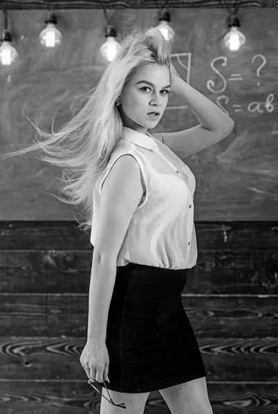 長いブロンドの髪を振って先生セクシーに見えます。夢のような顔の女性の厳しい先生は、黒板の前に立ちます。教室で白いブラウスに長い髪の女が立っています。女教師コンセプト — ストック写真