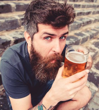 Hippi heyecanlı yüzüne açık bira içiyor. Cuma kavramı relax. Dinlenme soğuk fıçı bira ile dövme adamla. Sakal ve bıyık tutan cam taş merdivenle oturur iken bira ile olan adam