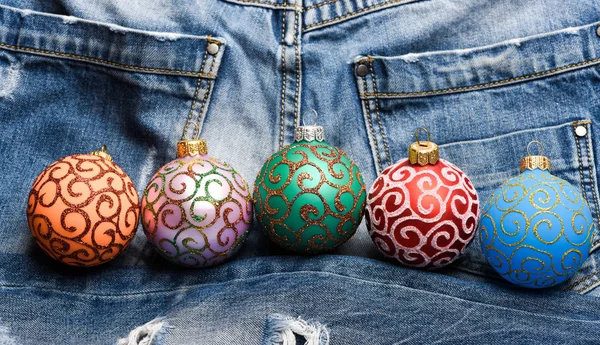 Christmas decorations concept. Pick colorful decorations. Modern christmas decor. Balls with glitter and shimmering decorative ornaments. Christmas ornaments or decorations on denim pants background