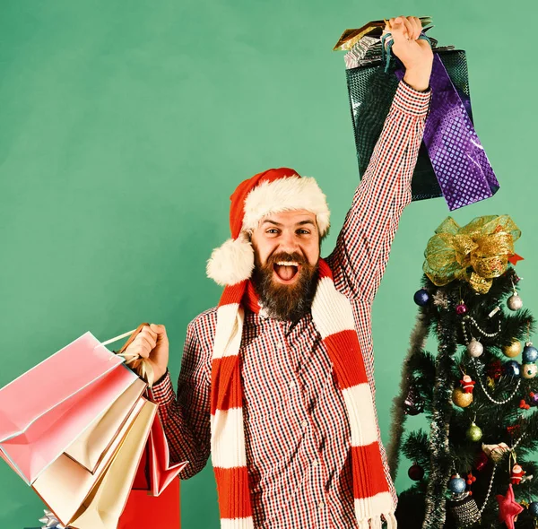 Man met rode hoed met boodschappentassen vol cadeautjes — Stockfoto