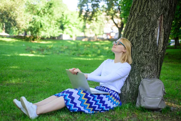 Бесплатный доступ к сети Wi-Fi. Серфинг в природе. Женщина с ноутбуком работает на открытом воздухе, в парке. Женщина-фрилансер работает в парке. Девушка сидеть трава постное дерево ствол с ноутбуком — стоковое фото