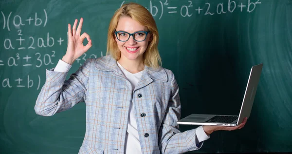 Opvoeder slimme slimme dame met moderne laptop zoeken informatie schoolbord achtergrond. Vrouw slijtage brillen houdt laptop surfen op internet. Geweldige bron voor leraren. Online onderwijs concept — Stockfoto