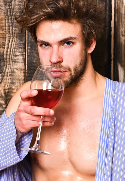Drink wine and relax. Guy attractive relaxing with alcohol drink. Man sexy chest wet skin after bath hold wineglass. Bachelor enjoy wine after bath. Macho tousled hair degustate luxury wine