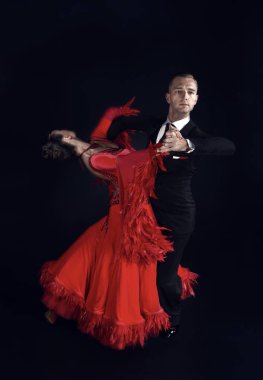 Kırmızı elbiseli dansçı çift siyah arka planda yalnız poz veriyor. Şehvetli profesyonel dansçılar walz, tango, slow fox ve quickstep dansı yapıyorlar..