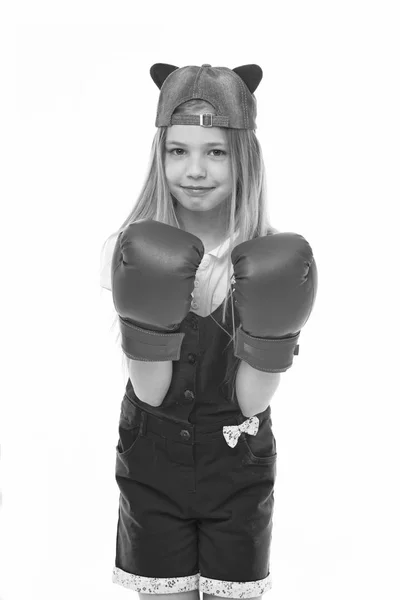 Lovely child wearing huge red boxing gloves. Girl in pink overalls isolated on white background. Kid wearing cute cap with animal ears backwards. Little fighter on training, self defence concept — Stock Photo, Image