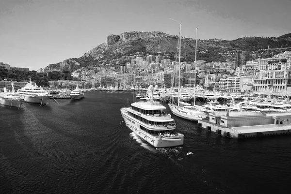 Monte Carlo, Monaco - December 08, 2009: ship go into sea harbor with houses on mountain landscape. Yacht club and city on summer seaside. Sea adventure and boat trips. Vacation and wanderlust — Stock Photo, Image