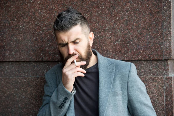 Il fumo e le abitudini concetto. Hipster con capelli eleganti viso concentrato premuroso con fumo bianco che vola fuori di bocca. Fumare all'aperto. Uomo con barba e baffi fumatori parete sfondo — Foto Stock