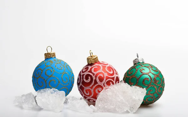 Três bolas de Natal decoração perto de pedras de gelo isolado em branco. Conceito de inverno e geada. Pedaços de gelo congelados perto de brinquedos de Natal. Temporada de inverno frio. Conceito de férias de inverno — Fotografia de Stock