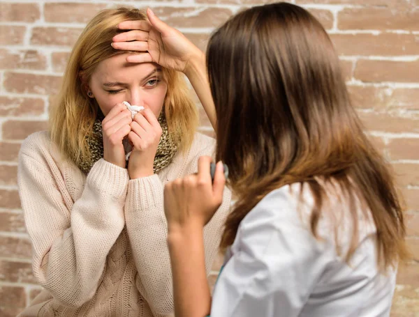 Woman feels badly ill sneezing. Girl in scarf hold tissue while doctor examine her. Recognize symptoms of cold. Remedies should help beat cold fast. Cold and flu remedies. Tips how to get rid of cold — Stock Photo, Image