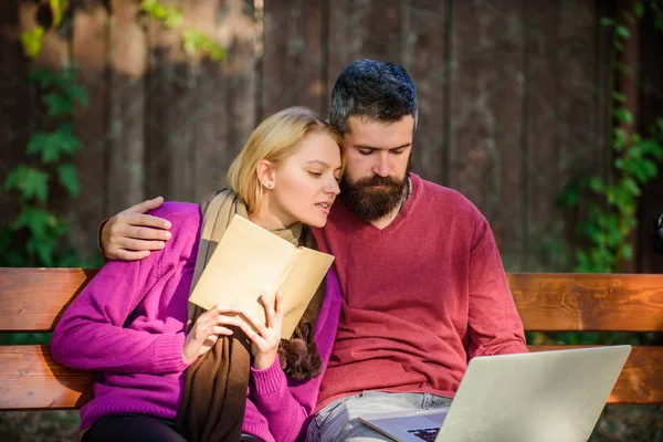 Couple with book and laptop search information. Information source concept. Share or exchange information knowledge. Man and woman use different information storage. Couple spend leisure reading