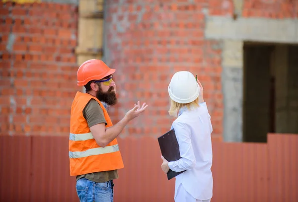 Building industrial project. Discuss progress project. Construction industry concept. Woman engineer and bearded brutal builder discuss construction progress. Construction project management