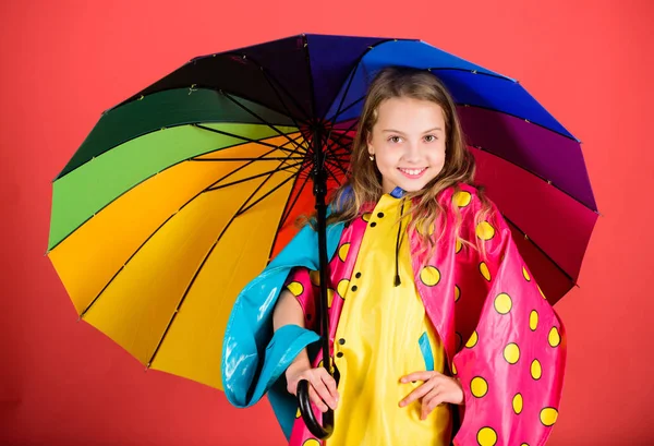 Užijte si deštivé počasí vlastního oblečení. Vodotěsné příslušenství vyrábět. Vodotěsné příslušenství aby deštivý den, veselá a příjemná. Šťastné dítě dívka drží Barevný deštník opotřebení Nepromokavý plášť — Stock fotografie