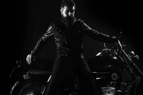 Macho, motociclista brutal em jaqueta de couro ficar perto de moto à noite, espaço cópia. Homem com barba, motociclista de jaqueta de couro magra na moto do motor na escuridão, fundo preto. Conceito de cultura de motociclista — Fotografia de Stock
