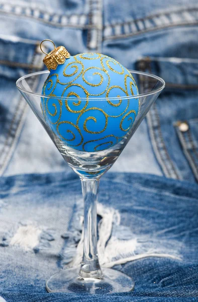 Bar winter season cocktail menu. Winter cocktail drink concept. Alcohol cocktail glass christmas ball ornament on denim background. Celebrate new year cocktail. Winter party alcohol drink