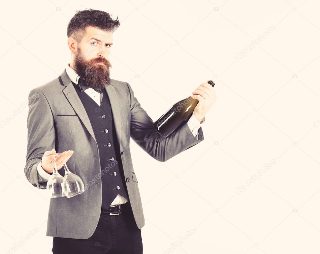 Perfect service, good manners, alcohol concept. Waiter with elegant suit, bow tie and handsome face. Mature man holds wineglasses and bottle of wine. Bearded man with calm face proposes wine