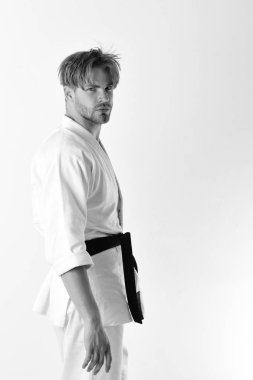 Adam siyah kuşaklı beyaz kimonoyla poz veriyor. Sağlıklı yaşam tarzı