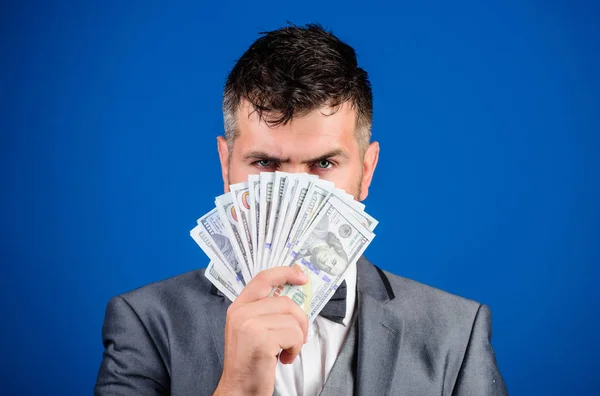 Get cash money easy and quickly. Smell of money. Easy cash loans. Man formal suit hold pile of dollar banknotes blue background. Businessman got cash money. Richness and wellbeing concept