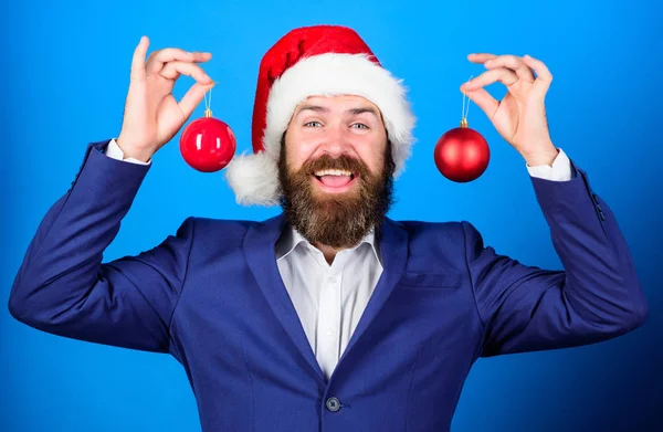 Man bearded wear formal suit and santa hat. Businessman join christmas celebration. Santa hold christmas ball decoration. Merry christmas. Christmas atmosphere spread around. Holidays meant for fun