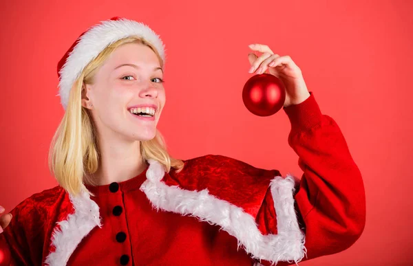 圣诞节的乐趣。女孩快乐穿圣诞老人服装庆祝圣诞节举行球装饰红色背景。圣诞准备理念。享受庆祝与服装和装饰。最喜欢的时间年圣诞节 — 图库照片