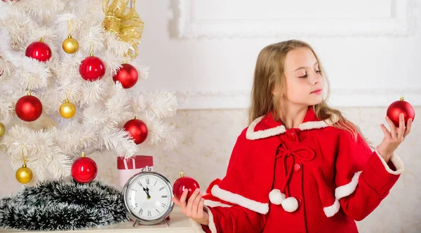 Deixe a criança decorar a árvore de Natal. Parte favorita de decoração. Envolver a criança na decoração. Menina sorridente rosto segurar bolas ornamentos fundo interior branco. Como decorar a árvore de Natal com a criança — Fotografia de Stock
