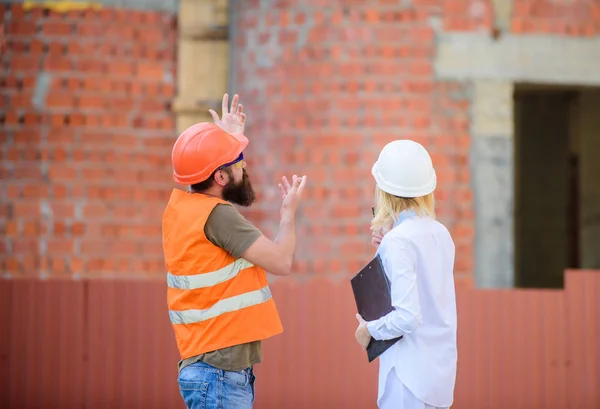 Construction project management. Building industrial project. Discuss progress project. Construction industry concept. Woman engineer and bearded brutal builder discuss construction progress