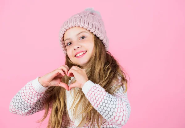 Kijk na de hoofdhuid en het haar deze winter. Winter haar schade te voorkomen. Winter hair care tips die u moet volgen. Kind lang haar lachend Toon hart gebaar. Meisje slijtage gebreide hoed roze achtergrond — Stockfoto