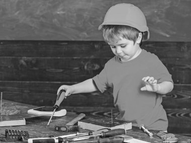 Çocuk Çocuk Tornavida Aracı tutar. Handcrafting ve atölye kavramı. Kask Oluşturucu veya repairer, veya handcrafting şirin çocuk. Yürümeye başlayan çocuk meşgul yüzündeki tornavida ile Atölyesi'nde oynamaktadır.